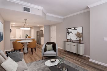 A modern living room with a grey sofa, a grey armchair, a white coffee table, and a grey rug
